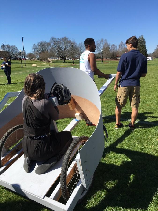 Senior Kameron Shook bracing herself for the chariot race, while fellow seniors Timothy Spivey and Kobe van Someren prepare to pull the chariot.