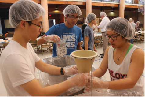 Students work to fill meal packets. (Pictured from L to R: Andy Zhao, Gary Nguyen, Jenny Nguyen)