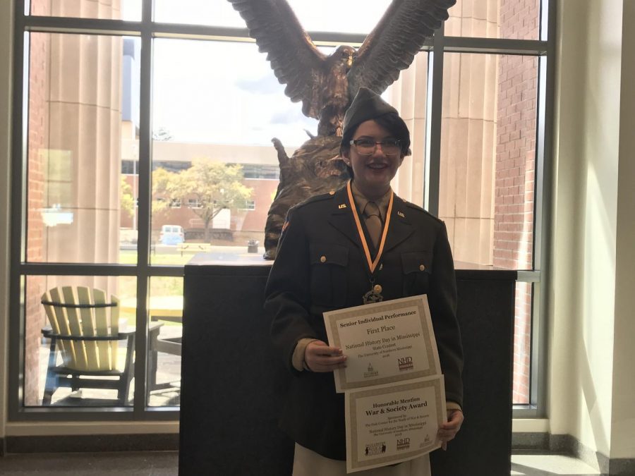 Sarah Perry posing with her awards from first place in Individual Performance and honorable mention in War and Society. 