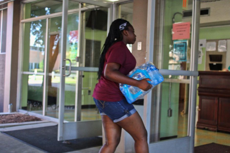 Senior Violet Jira carries in a pack of water during move in day.