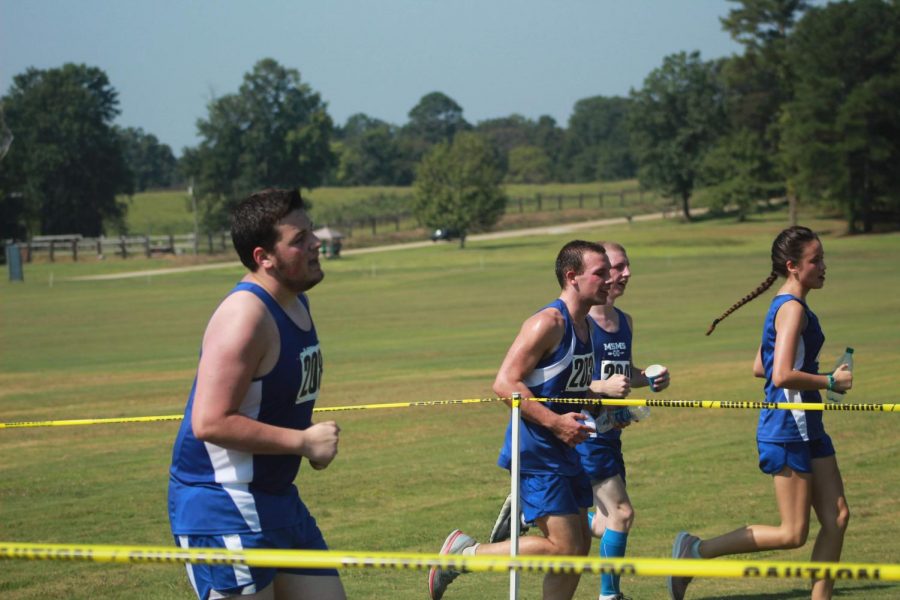Senior Will Sutton powers through the last section of the run while his teammates cheer him on beside him.