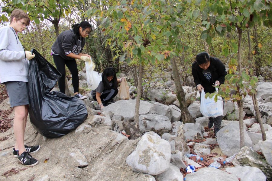 Students gather to dig plastic bottles from under dirt and rocks.