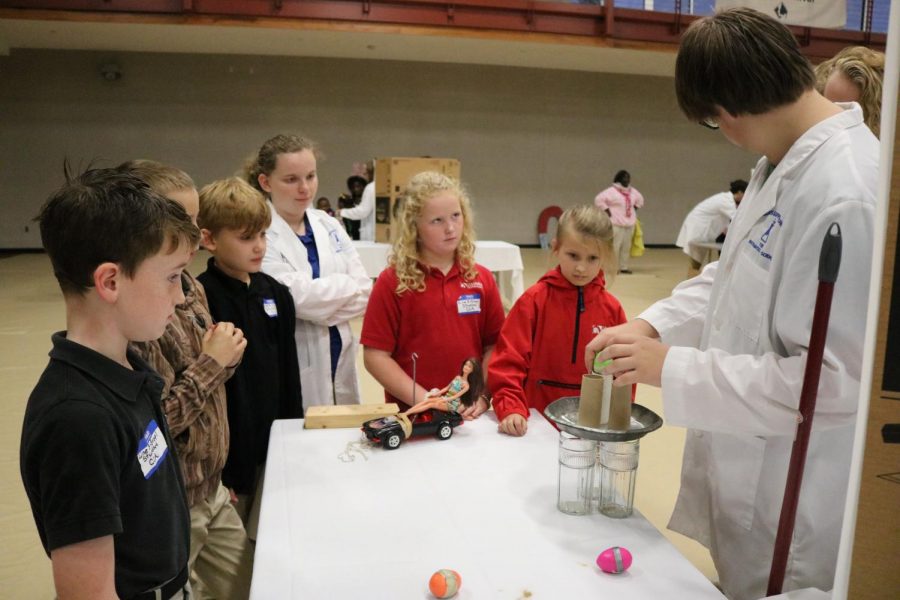Several elementary students look on as MSMS students demonstrate inertia.