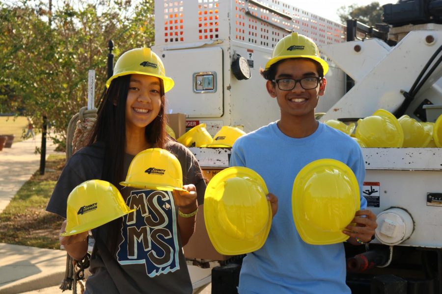 Nina Vo (left) and Shanay Desai (right) hands out hard hats on behalf of the 4 County Electric Power Association.