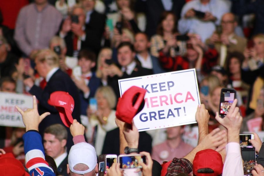 The crowd cheers after Trump finishes speaking, while holding up their Keep America Great! signs and hats.