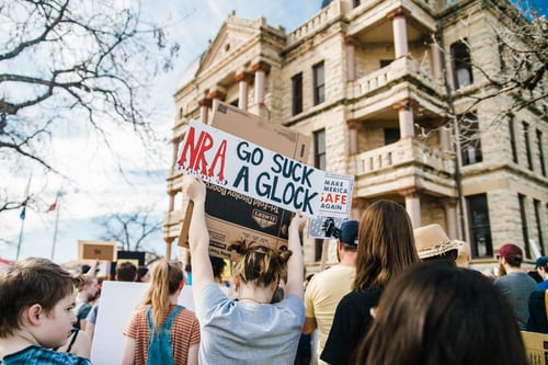 A marcher holds up a sign reading, NRA go suck a glock.