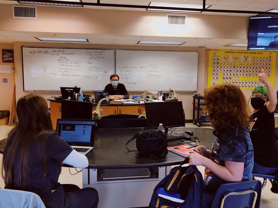 Students participate in an in-person physics class while one classmate joins from Zoom.