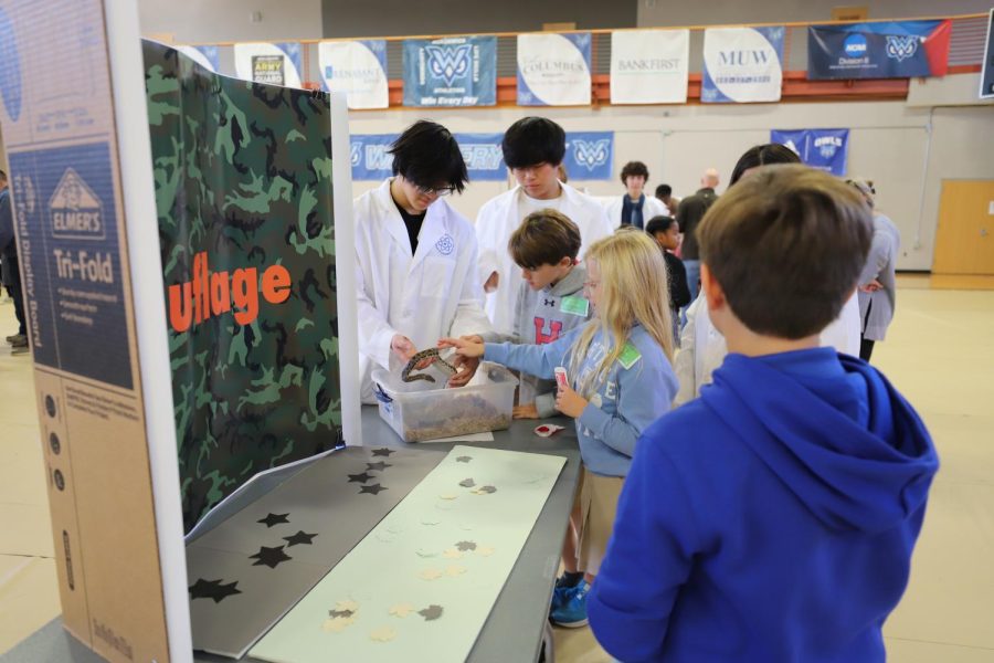 Juniors Justin Doan and Max Feng demonstrate camouflage to elementary school students.