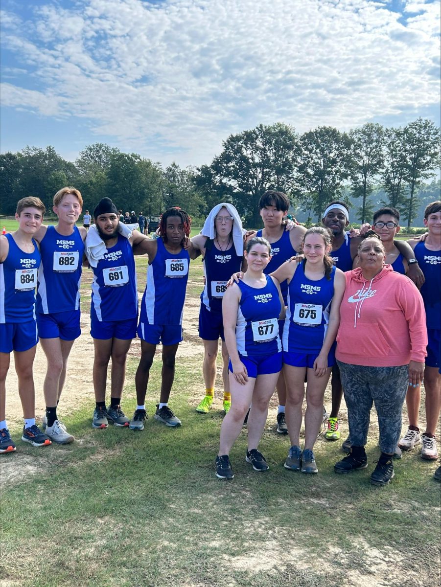 Coordinator for Activities Veleria Scott and the MSMS cross-country team pose together Saturday after the Blue Waves’ successful run at the Mooreville meet. The team will travel to Saltillo Friday for its next meet. 