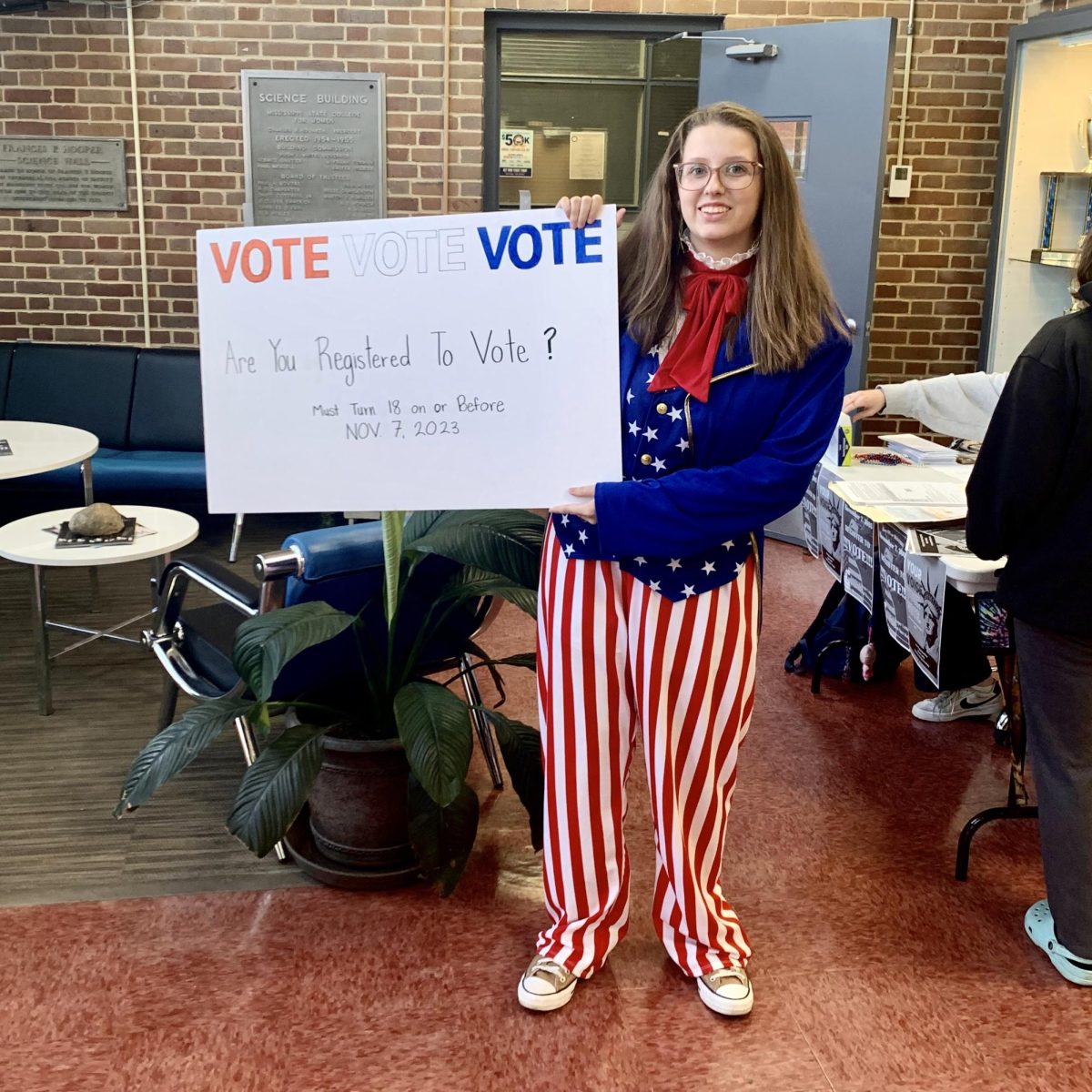 Young Democrats Club President Ava Noe holds up a sign encouraging eligible students to register to vote at YDCs September voter registration drive. The drive helped all 16 MSMS students eligible for the 2023 General Election register to vote.