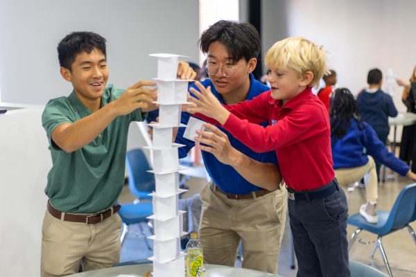 Junior Daniel Van (left) and senior Ean Choi (center) build an index card tower with a local elementary school student for one of MO-Maths Math Superstars activities on Oct. 31. 