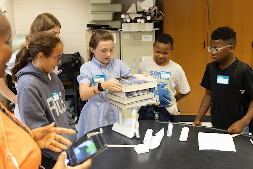 A group of elementary school students, led by senior Clara Jennings, construct a paper tower in Math Outreach's engineering activity.